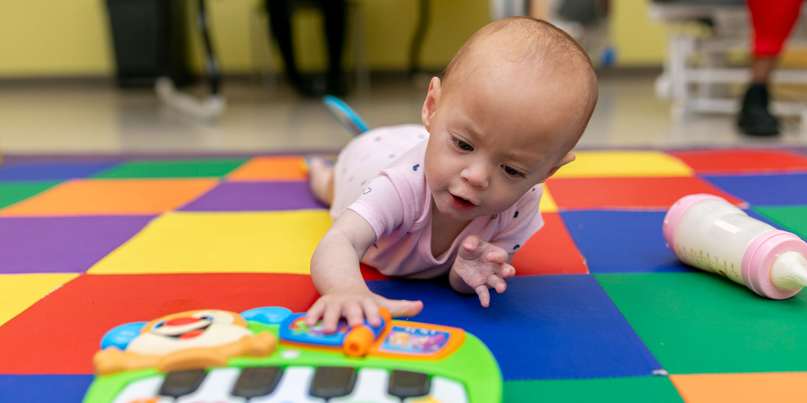 baby playing with a toy keyboard on colorful mat