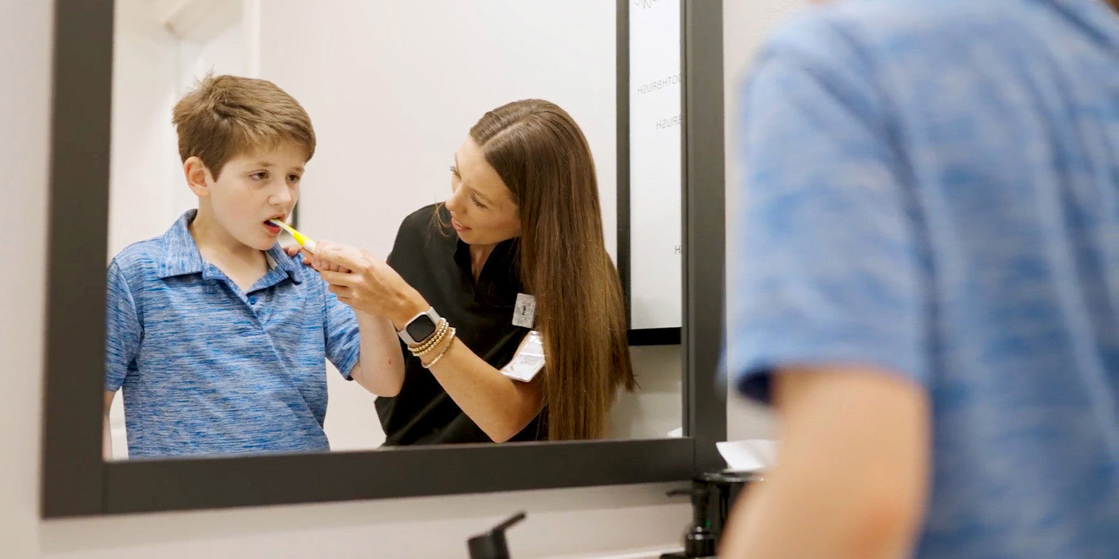 child receiving help learning to brush their teeth